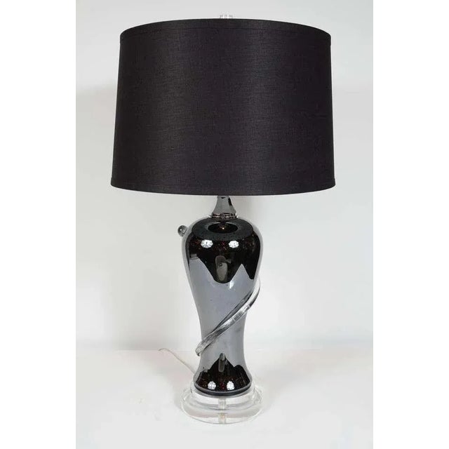 Modernist black hand blown glass urn shaped lamp with a raised swirl pattern in translucent glass, a tiered lucite base...