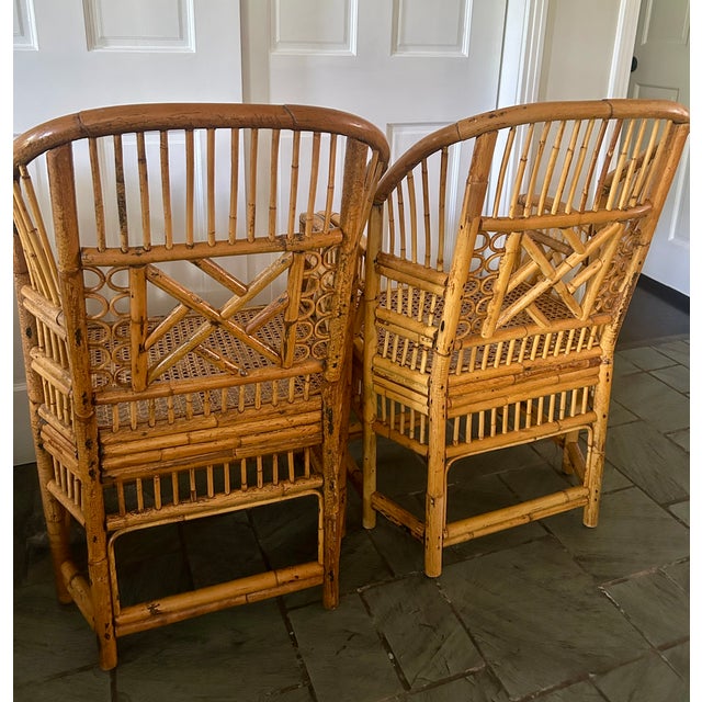 A striking pair of Brighton Pavilion style bamboo armchairs featuring gracefully arched backs, woven cane seats, and...