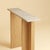 Two materials, one line. The Maha is a slim, upright table made to sit against a wall, its travertine surface carried on a...