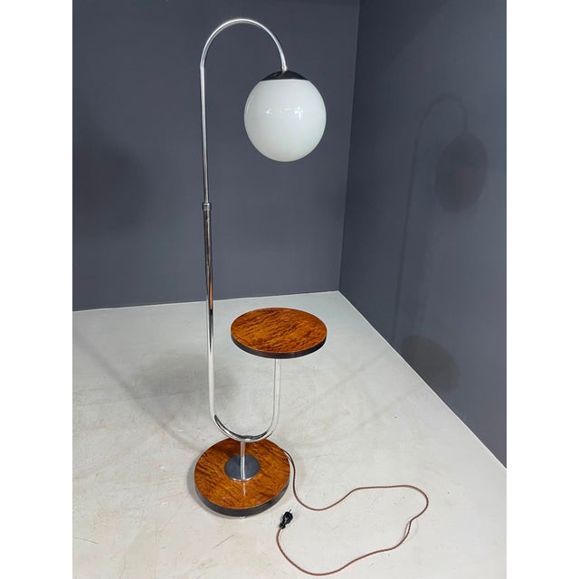 A distinctive bauhaus-style floor lamp with an integrated side table, attributed to r. Slezák and dating from the 1920s....