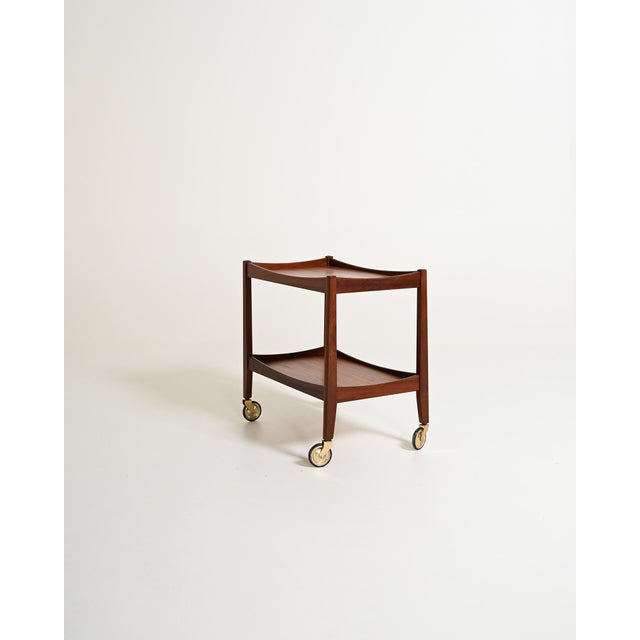 Teak trolley with two shelves, a contoured top edge, and casters with brass supports. Scandinavian production, 1960s. Made...