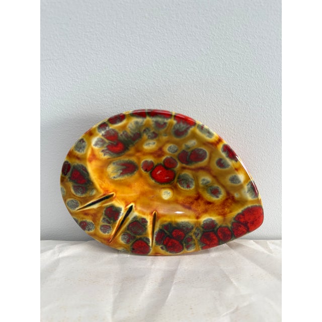 A bold and sculptural mid-century studio pottery ashtray featuring an exceptional amber-orange reactive glaze with...