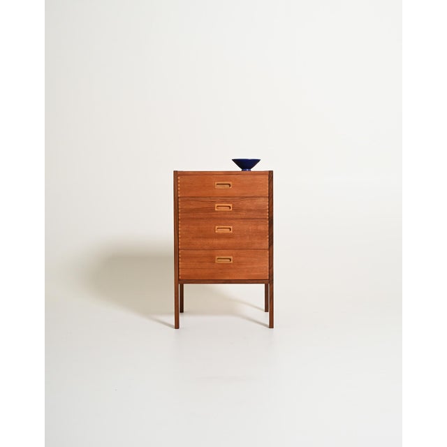 Teak frame with four drawers, light ash side panels, recessed handles, and dovetail joints. Gillis Lundgren, 1960s. A...