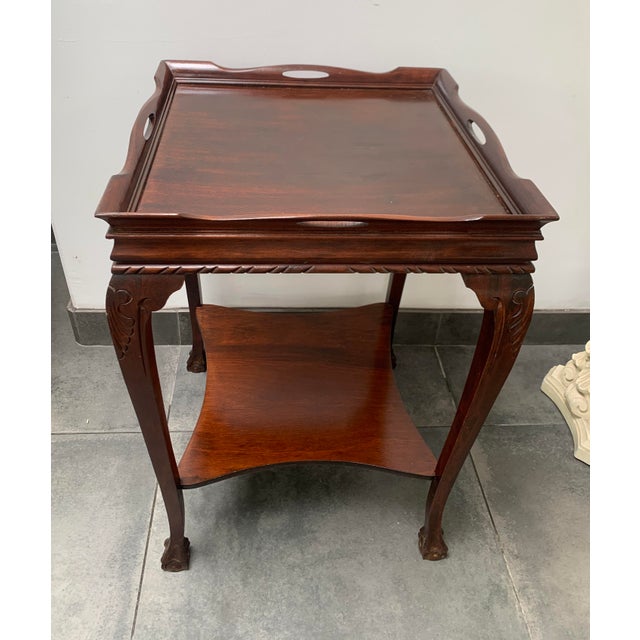 A hand carved, two tiered, square side table made from nicely carved mahogany in Chippendale style. The table features a...
