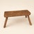 A humble, hard-working little stool hewn from a single thick plank, standing on four splayed round legs pegged through the...