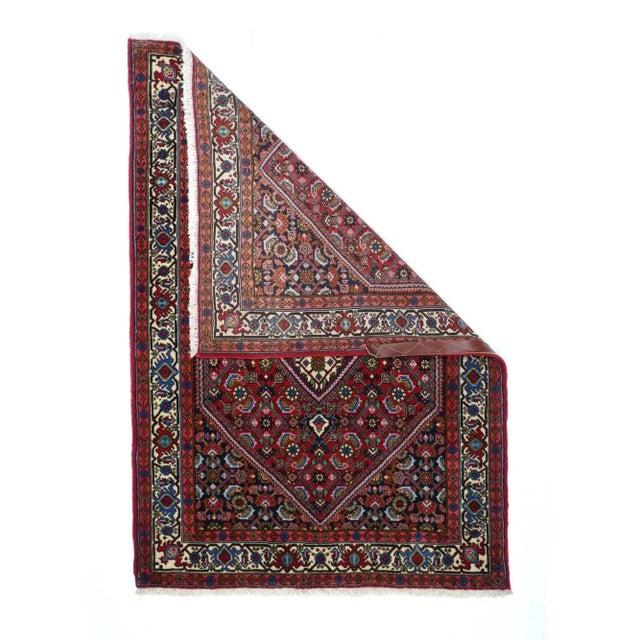 The red field uniformly displays an allover four column Herati design of palmettes, rosettes, curved leaves and open...