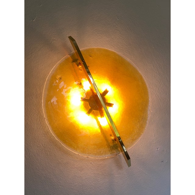 Impressive Italian Fashion Wall Light in Amber Murano Glass Disc and Brass Metal Frame Murano glass disc in amber with...
