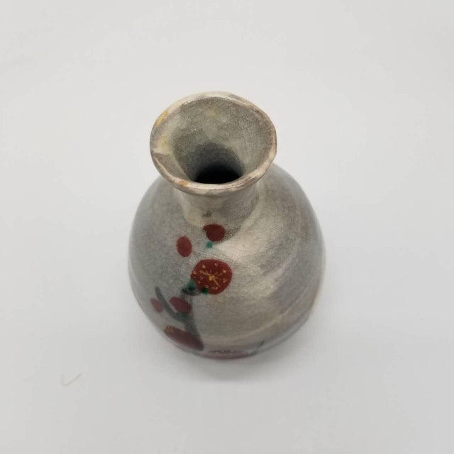 A vintage Japanese Tokkuri (sake bottle) featuring a hand-painted Ume (plum blossom) design, symbolizing elegance,...