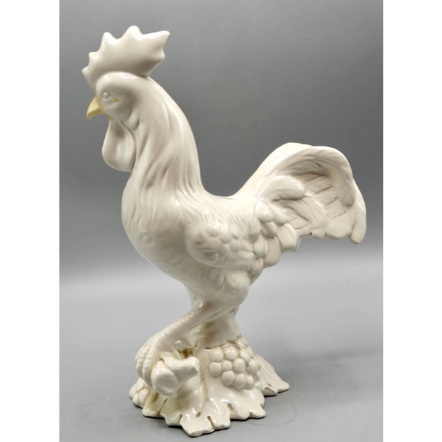 A Mid 20th-Century Italian blanc de chine rooster figurine perched upon a bunch of grapes and leaves, It is fine,...