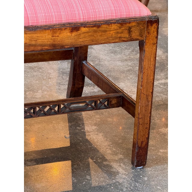 An 18th century English mahogany hall bench with a triple chair back, each back with an interlaced pierced splat ending in...