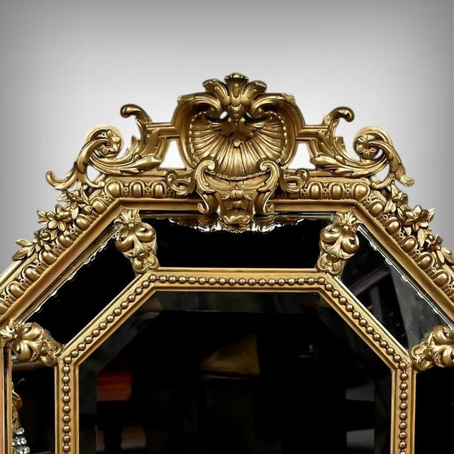 Elegant octagonal mirror with beveled glass in the Louis XV style. Made of stuccoed and gilded wood, the frame is richly...