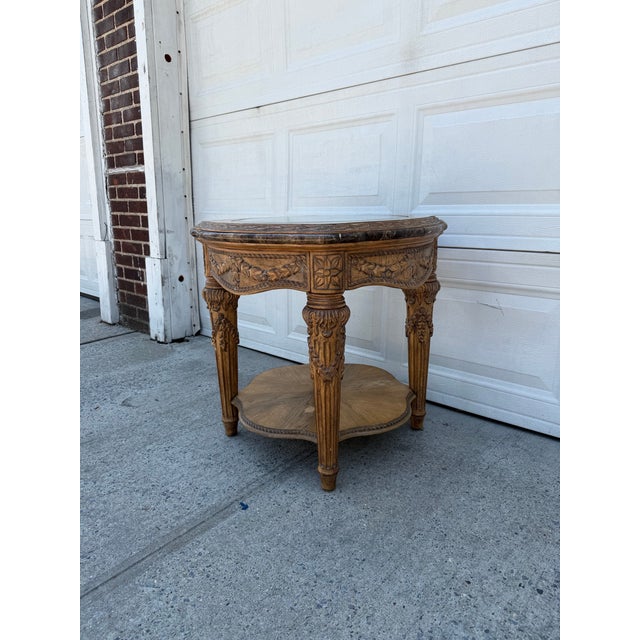 We have a beautiful vintage Louis XVI Revival side table for sale featuring ornate carved wood, an inset glass top, and...