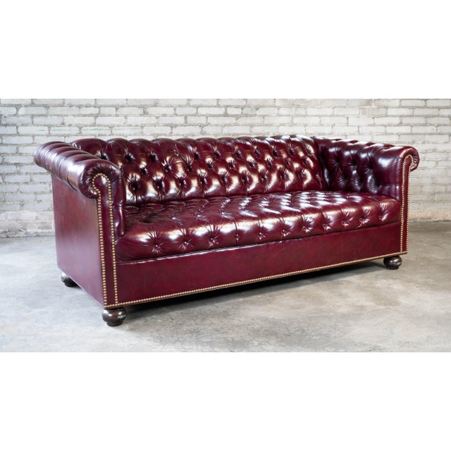 Lovely English Traditional Chesterfield sofa, presented in a diamond button tufted vibrant oxblood leather. Brass nailhead...
