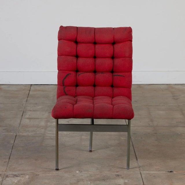 Tripod chrome base chair with tufted red upholstery.