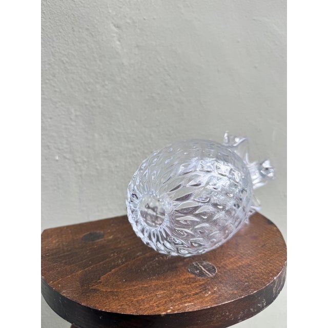 A delightful clear glass pineapple candle holder with a finely textured diamond-faceted body catching and refracting light...