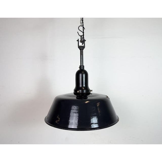 Industrial black enamel pendant light made in Germany during the 1950s. White enamel inside the shade. Porcelain top. The...