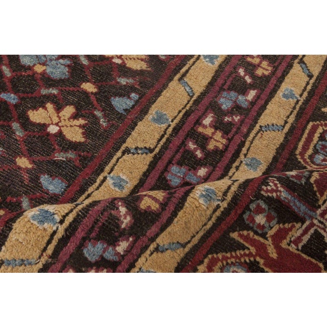 An early 20th century indian area rug, the dark brown field with a miniature diamond trellis overall containing small blue...