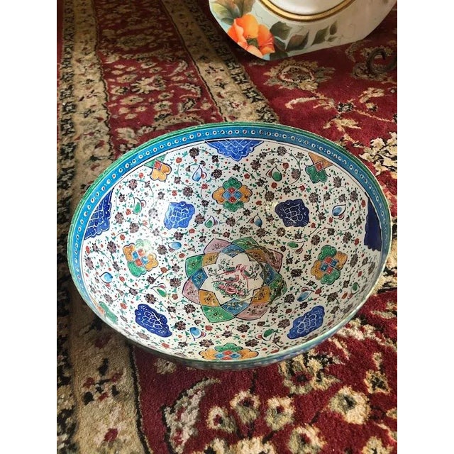 Hand-painted by master artisans, this bowl features intricate figurative art and ornate geometric patterns, showcasing the...