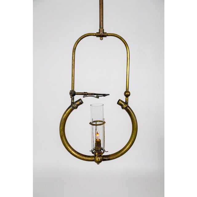 An antique, hanging pressure-style gas lamp. Comprised of a brass harp structure topped with a stem and globular font,...