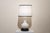 A 1960s vase table lamp. The structure consists of, from bottom to top, a circular, molded black wooden base and a...