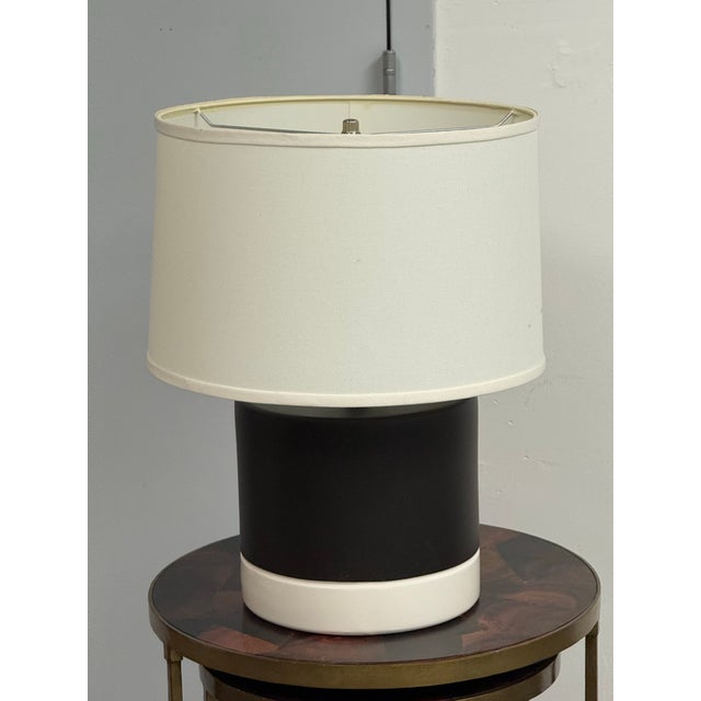 Design Plus Gallery presents a Ceramic Table Lamp. The table lamp has matte black cylindrical body, glossy white ceramic...