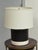Design Plus Gallery presents a Ceramic Table Lamp. The table lamp has matte black cylindrical body, glossy white ceramic...