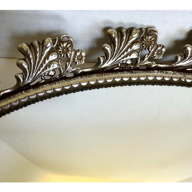 This elegant vintage oval vanity mirror dates to the mid-20th century, circa 1960s, and features a beautifully detailed...