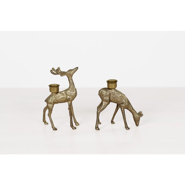 Vintage brass deer taper candle holders, a pair featuring a stag with head raised and full antlers, and a doe in a grazing...