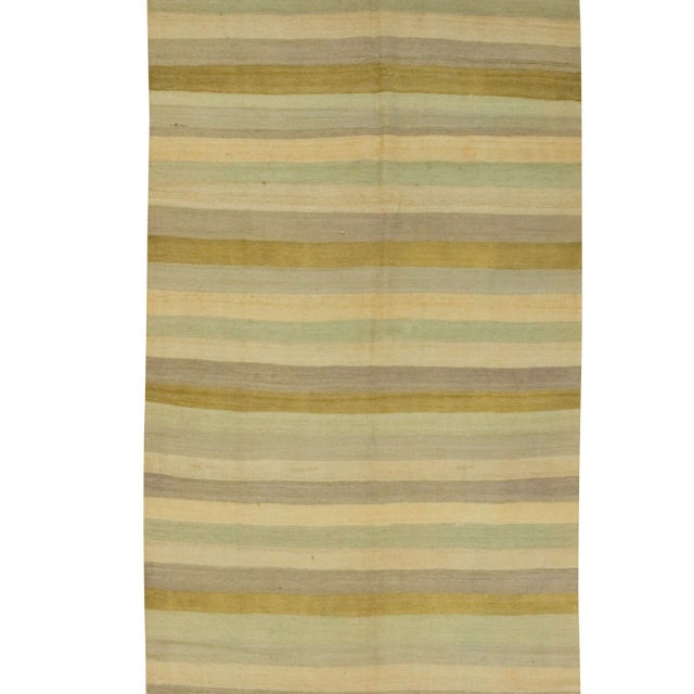 This vintage Turkish kilim runner, handwoven in the 1940s, features a striking striped design in green, cream, and...