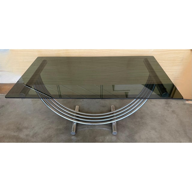 Sculptural Art Deco style dining table in the Romeo Rega Style. Curved arch tubular base features brass and chrome striped...