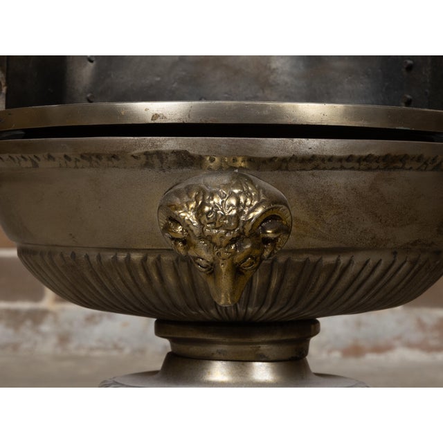 An English Regency style coal burner fireplace urn grate from the 19th century with brass volutes and ram's head. This...