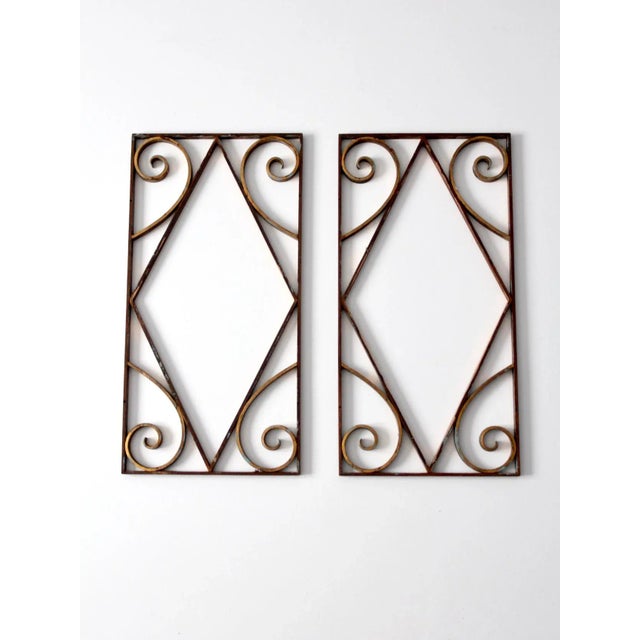 This is a pair of antique brass architectural pieces. The decorative metal frames feature diamond and swirling flourishes....