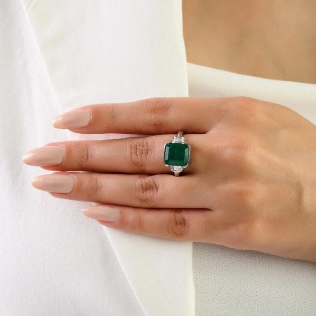 This Art Deco-style ring features a 1 octagon cut emerald totaling 4.37 carats, set in rich 14k white gold. The emerald...