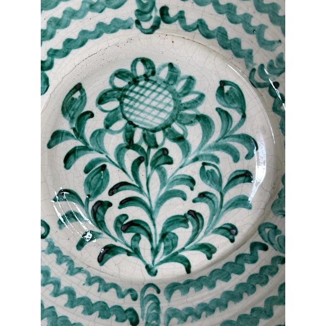 A generously sized Fajalauza bowl from Granada, adorned with a radiant daisy at the center, surrounded by elegant leafy...