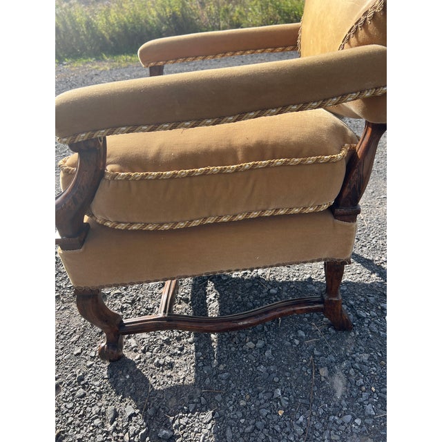 Vintage French Regence style armchair upholstered in rich gold velvet. Features an embroidered heraldic coat of arms crest...