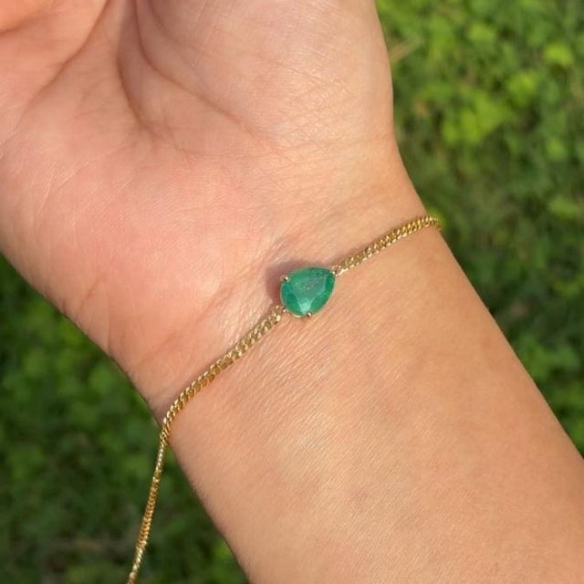 This minimalist 1.85 carat pear-cut emerald solitaire chain bracelet is crafted in 14K yellow gold. The emerald measures...