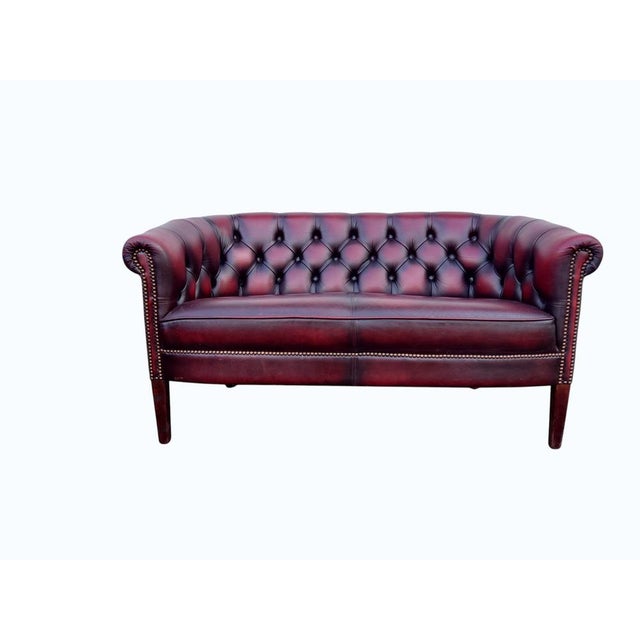 A striking vintage English Chesterfield lounge group in rich oxblood red leather, comprising two two-seater sofas and one...