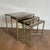 This set of three neoclassical-style nesting tables is made of brass with glass shelves surrounded by a line of silver-...