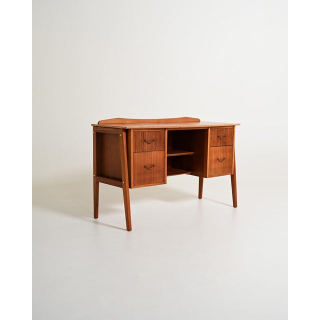 Teak desk with four drawers, a central compartment with two shelves, and tapered legs. Scandinavian design, 1960s....