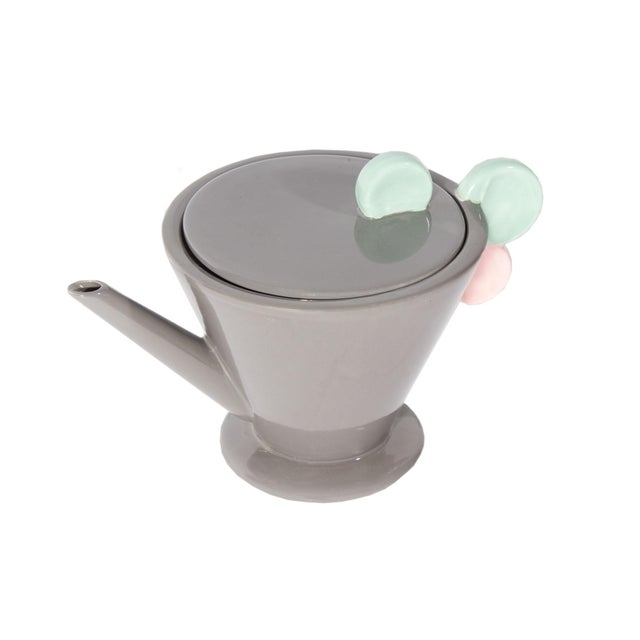 A Postmodern ceramic teapot produced by Mikasa. The gray teapot has a blue and pink circular handle and the lid has a blue...