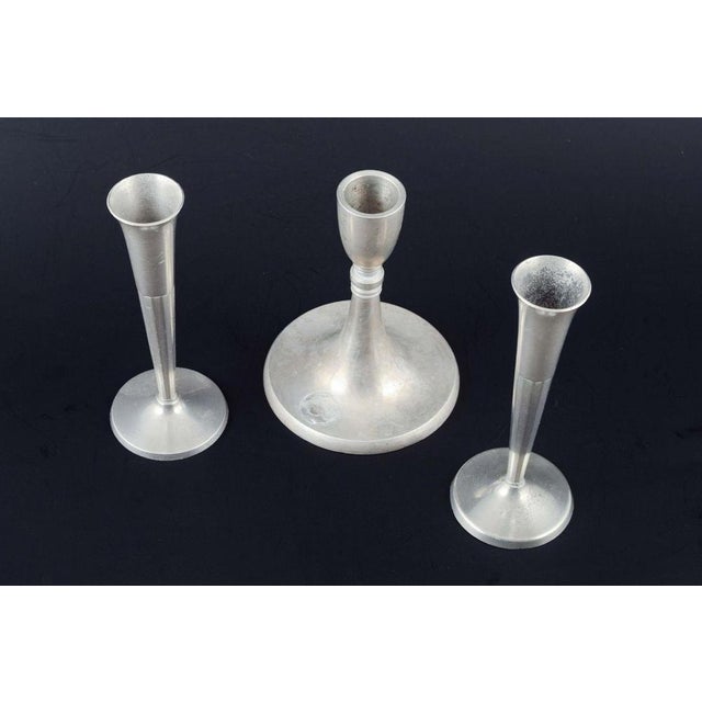 Three pewter candlesticks. One danish candlestick by just andersen, denmark, and two slender examples stamped selangor...