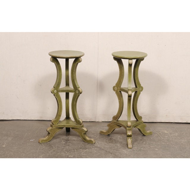 A French pair of carved and painted wood three tier pedestals from the mid 20th century. These mid-century pedestals from...