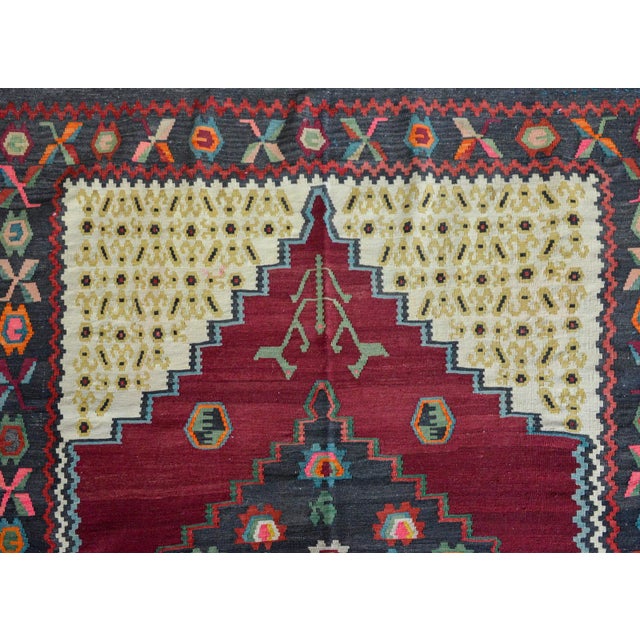 A wonderful vintage Armenian kilim rug with a central medallion with stylized flowers woven in myriad colors against a...