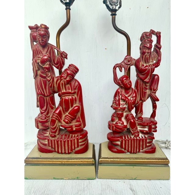 A striking and finely executed pair of antique Chinese carved wood table lamps depicting revered Immortals—one a fisherman...