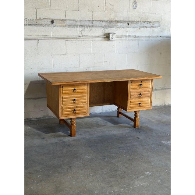 A substantial oak desk by Henning Kjærnulf pairs a broad rectangular top with two banks of three drawers. Sculpted drawer...