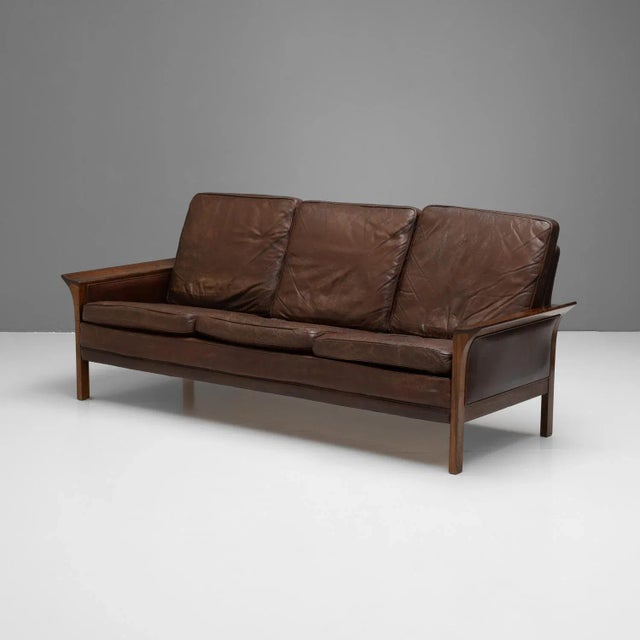 Mid-20th Century leather sofa in the manner of Hans Olsen. Solid rosewood arms and legs with a beech frame. Original well-...