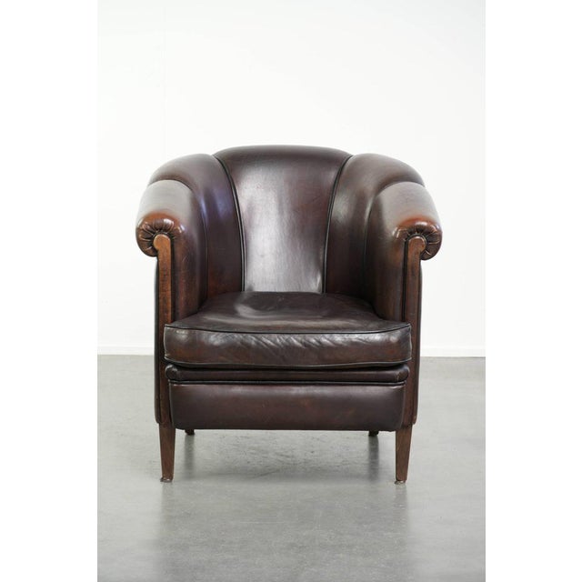This dark sheepskin club armchair in the English style features a unique design and a desirable patina. It comes with a...