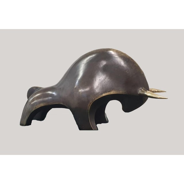 A contemporary abstract bronze of a bull, the animal reduced to a single massive, rounded volume balanced on short, bowed...