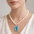 Striking 14K yellow gold necklace featuring an octagonal blue topaz (50.25 Carat Total Weight) Surrounded by 52 round...