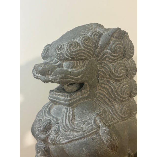 A striking pair of vintage hand carved stone Foo Dogs, also known as Guardian Lions, featuring exceptional hand carved...